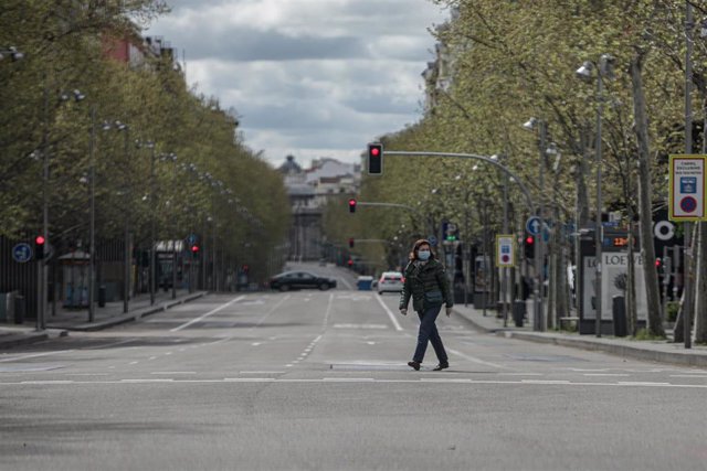 Una mujer pasea con mascarilla por el cruce entre la calle Serrano y la calle Ortega y Gasset, vacío durante el estado de alarma, a 22 de marzo de 2020.