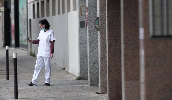 Una sanitaria con mascarilla consulta su móvil en la puerta del garaje del Hotel City House Florida Norte