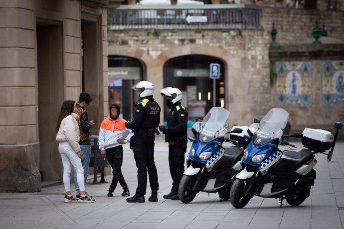 Dos agents de Policia parlen amb tres joves durant el segon dia laborable de l'estat d'alarma pel coronavirus, a Barcelona/Catalunya (Espanya), a 17 de mar de 2020.