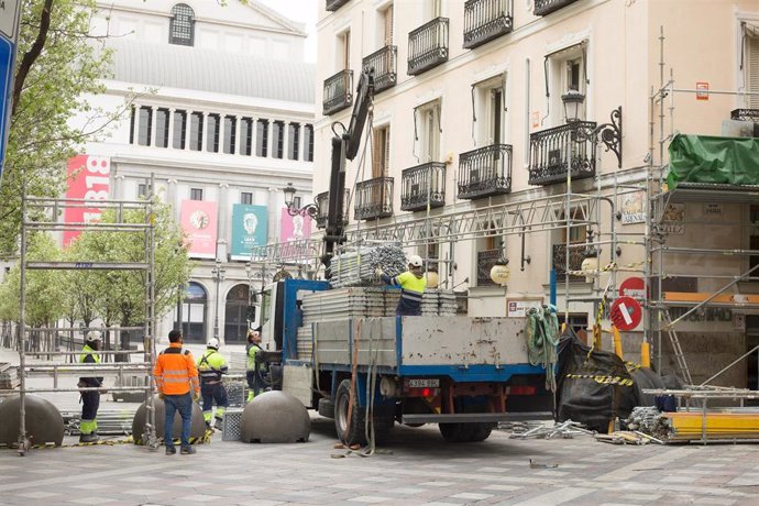 Varios obreros desmontan los andamios que ocupan las fachadas de algunas casas en la Calle Arenal de Madrid