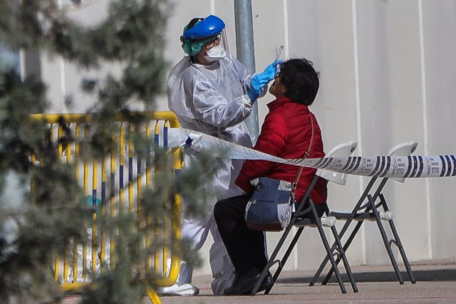 Una sanitaria realiza a una trabajadora de servicios esenciales uno de los test rápidos de coronavirus, en Madrid (España), a 25 de marzo de 2020.