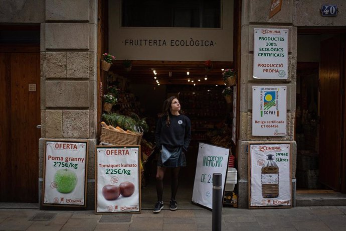 Una dona en la porta de la seva frutería ecolgica durant el primer dia laborable de la segona setmana des que es va decretar l'estat d'alarma al país a conseqüncia del coronavirus, a Barcelona/Catalunya (Espanya) a 23 de mar de 2020.