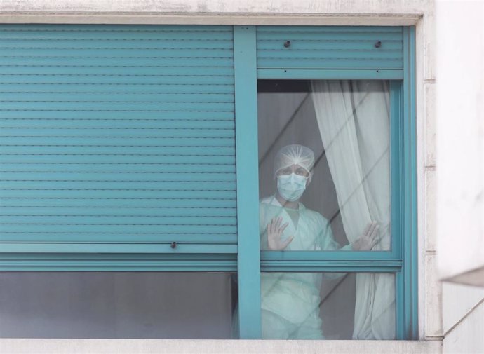 Una trabajadora del personal sanitario protegida con mascarilla se asoma por una de las ventanas de la Residencia ORPEA Madrid 