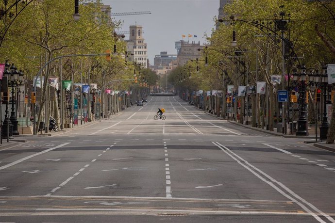 Un trabajador en bicicleta por el Paseo de Gracia, en Barcelona/Catalunya (España) a 23 de marzo de 2020.