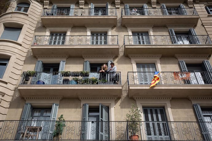Dues persones treuen el cap a la balconada durant el tercer dia laborable de l'estat d'alarma per coronavirus, a Barcelona/Catalunya (Espanya) a 18 de mar de 2020.