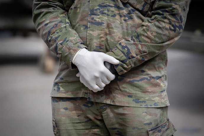 Manos de uno de los militares del ejército protegido con guantes que custodia el pabellón de la Fira de Barcelona que ya está habilitado para acoger a personas sin hogar en plena crisis del coronavirus, en Barcelona.