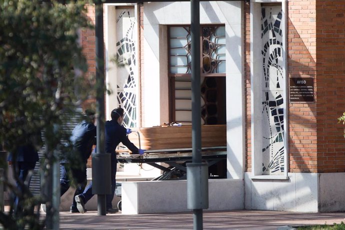 Dos trabajadores introducen un ataúd por la puerta de la funeraria municipal de Madrid 