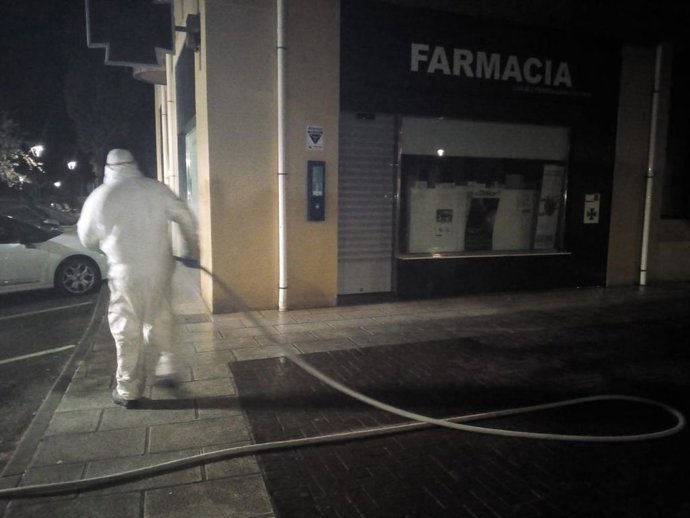Efectivos del plan de limpieza y desinfección trabajan en el exterior de una farmacia