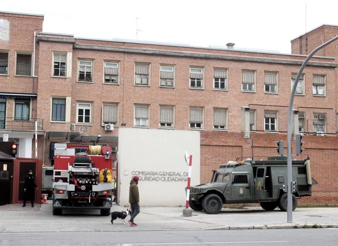 Una persona protegida con mascarilla pasea a un perro justo en el momento en el que un camión con militares de la UME a bordo llegan a la Comisaría General de Seguridad Ciudadana ubicada en Francos Rodríguez (Madrid)