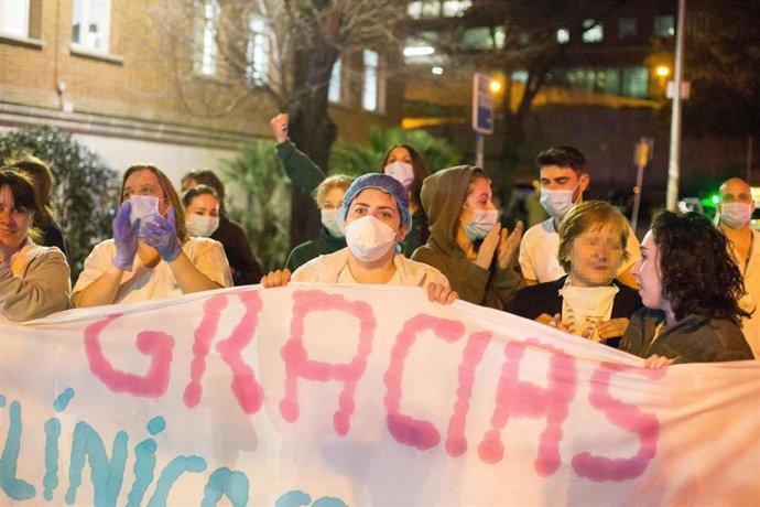 Un grupo de trabajadoras sanitarias aplauden y sostienen una pancarta en agradecimiento al Hospital Clínico San Carlos