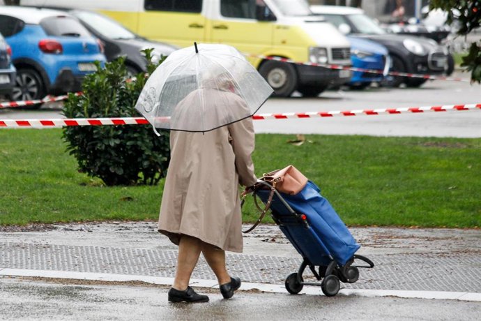 Una mujer se protege de la lluvia de Madrid durante el sexto da del estado de alarma por coronavirus, en Madrid (Espaa) a 21 de marzo de 2020.