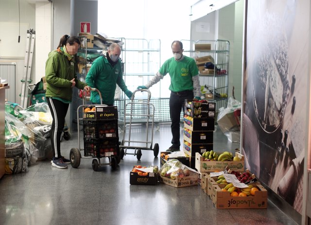 Tres trabajadores del Mercado municipal de Barceló preparan varias cajas de fruta que  serán repartidas a lo largo de la mañana de hoy en el hospital de Ifema 