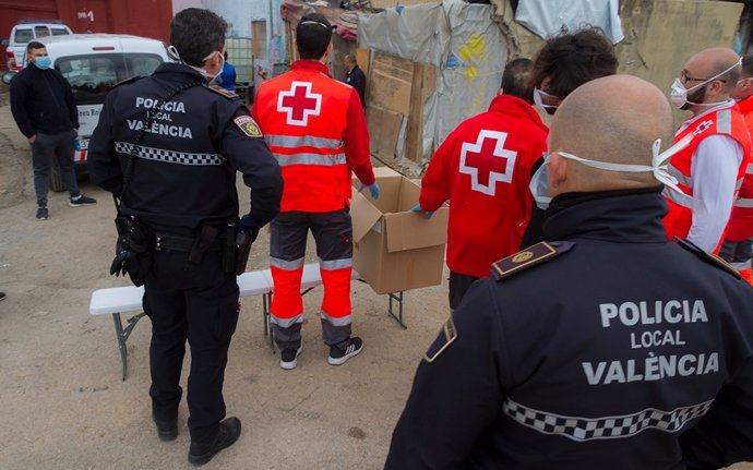 Agentes de la Policía Local y voluntarios de Cruz Roja repartene productos de primera necesidad a personas sin hogar en Valncia