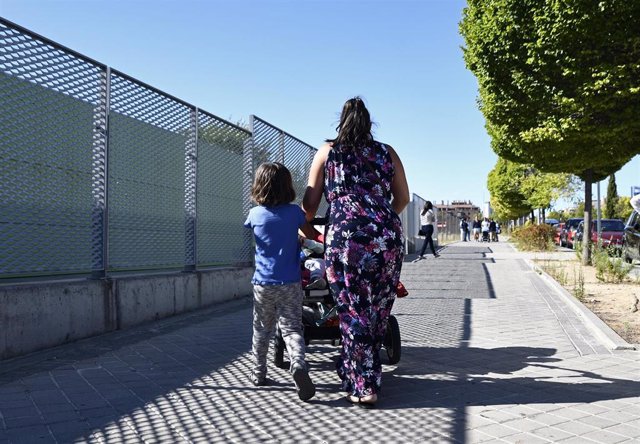 Una madre y su hijo empujan el carrito de un bebé en un parque de Madrid.