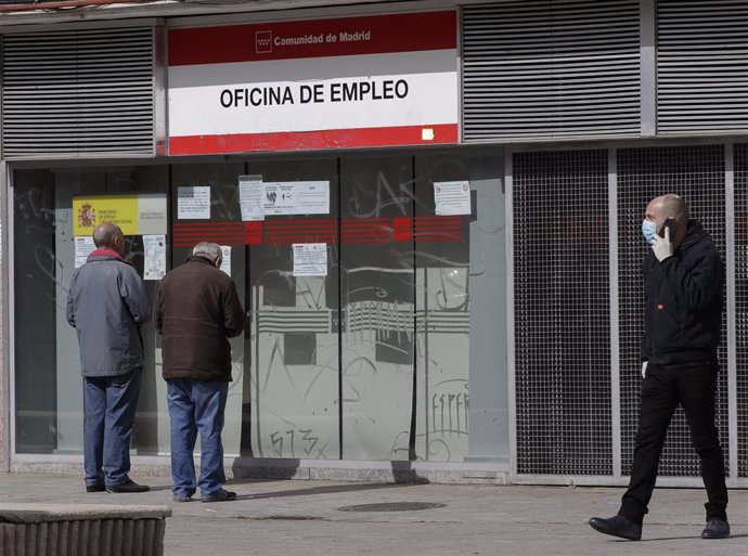 Dos hombres leen los carteles de una oficina de empleo cerrada,en Alcorcón 