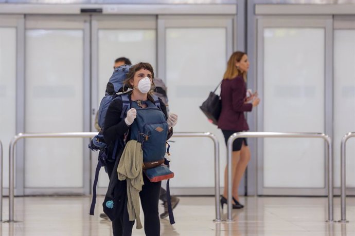 Una mujer protegida con mascarilla recoge su equipaje de la Terminal 4 del Aeropuerto Adolfo Suárez-Madrid Barajas 