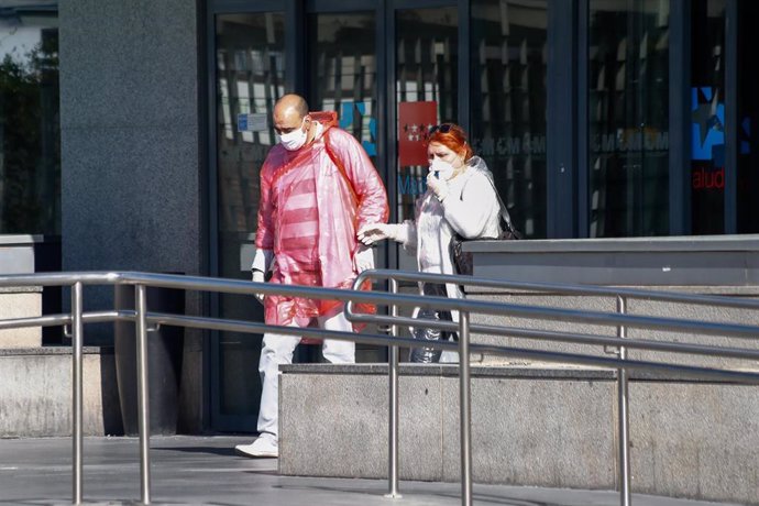 Dos personas protegidas con mascarillas salen del Hospital La Paz, centro en cuyas dependencias se ha instalado una carpa que sirve como ampliación de las Urgencias del centro y donde se atiende a pacientes sospechosos de coronavirus