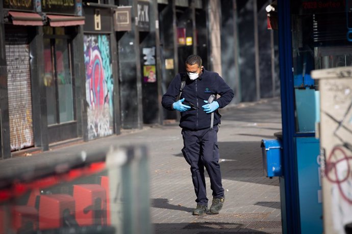 Un home protegit amb mascarilla i guants camina per un carrer durant el nov dia laborable des que es va decretar l'estat d'alarma al país a conseqüncia del coronavirus, a Barcelona/Catalunya (Espanya) a 26 de mar de 2020.