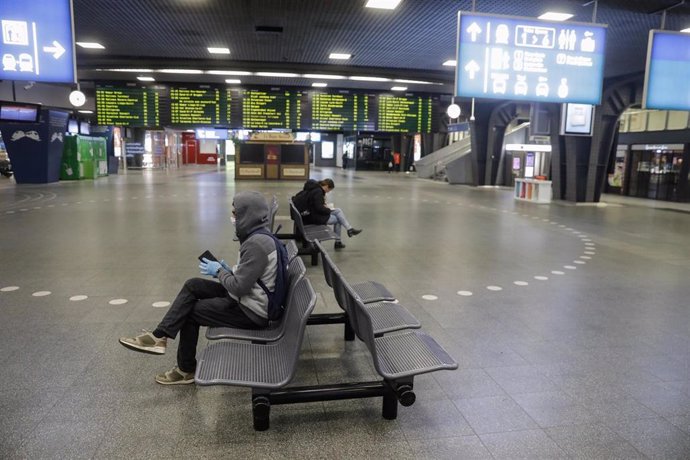 Pasajeros en una estación de trenes de Bruselas con mascarilla por el coronavirus