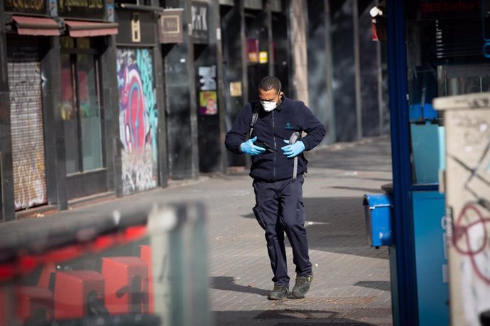 Un home protegit amb mascarilla i guants camina per un carrer durant l'estat d'alarma.