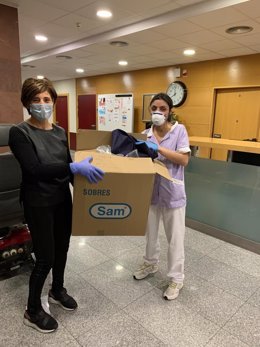 Una enfermera voluntaria entrega una caja de batas de aislamiento para el personal de la Residencia Torre Monreal de Tudela