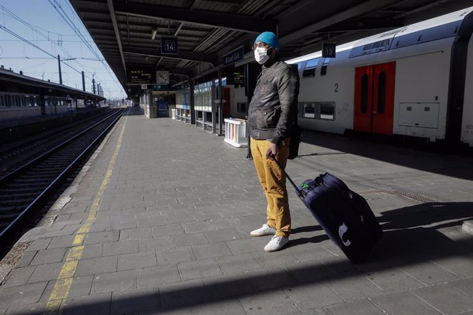 Un hombre con mascarilla espera a un tren en un andén de una estación de Bruselas
