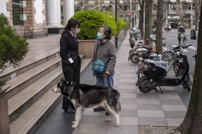 Dos mujeres con mascarilla dialogan en las calles de Shanghai.