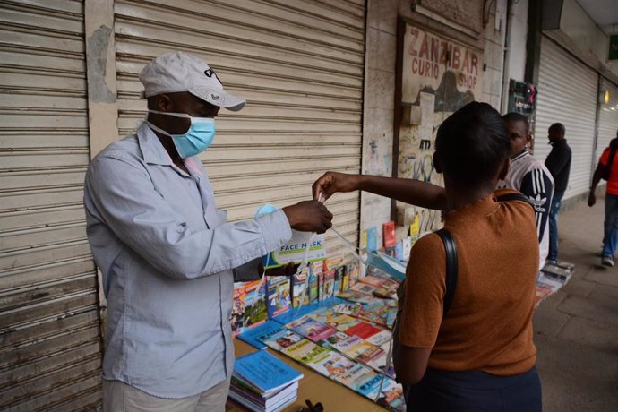 Una mujer comprando a un vendedor con mascarilla en Nairobi