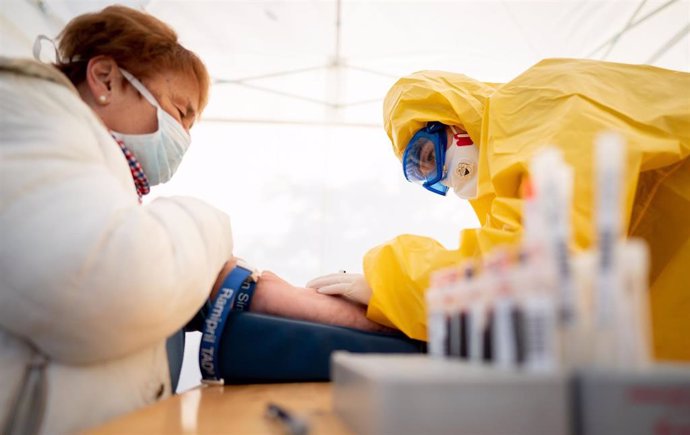 30 March 2020, Berlin: Nina Leimer (R), 20, paramedic and second semester medical student, takes a blood sample from a woman at a tent, for possible detection of antibodies against the coronavirus. Photo: Kay Nietfeld/dpa