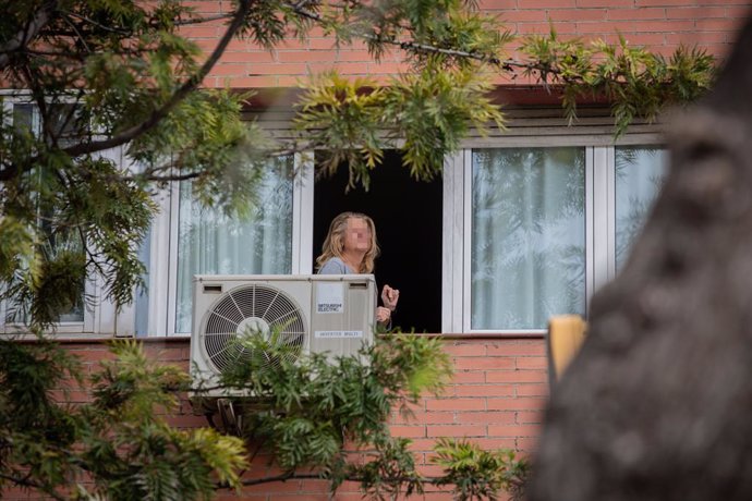 Una dona treu el cap a la seva finestra durant el primer dia laborable de la segona setmana des que es va decretar l'estat d'alarma al país a conseqüncia del coronavirus, a Barcelona/Catalunya (Espanya) a 23 de mar de 2020.