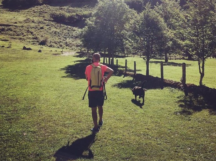 Un hombre pasea con su perro por un paraje natural.