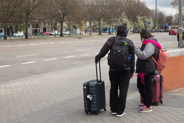 Dos turistas con maletas, uno de ellos con mascarilla, a su salida de la estación de Atocha. 
