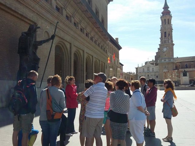 Un grupo de turistas visitan la plaza del Pilar. 