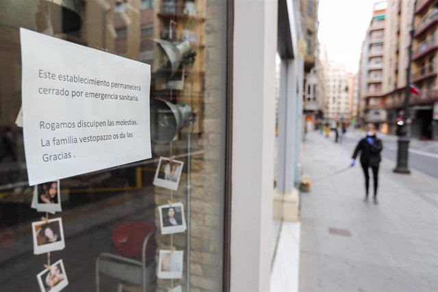 Cartel en la ventana de un establecimiento cerrado en una calle prácticamente vacía durante el segundo día laborable de la segunda semana desde que se decretó el estado de alarma en el país a consecuencia del coronavirus, en Valencia (Comunidad Valenciana