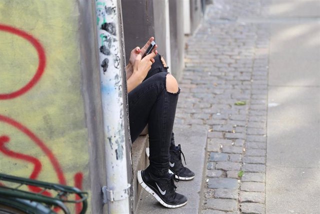 Una adolescente con un móvil en la calle.