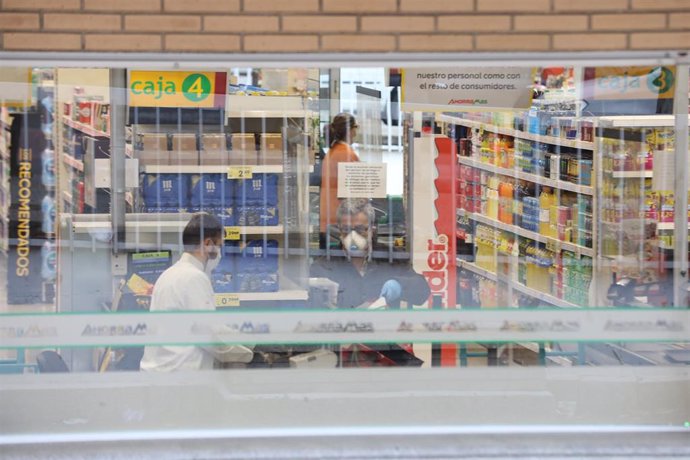 Un cajero de un supermercado AhorraMas trabaja protegido con mascarilla en plena crisis sanitaria por coronavirus donde los españoles llevan confinados en sus hogares más de una semana y la gran mayoría de establecimientos que no son de primera necesidad