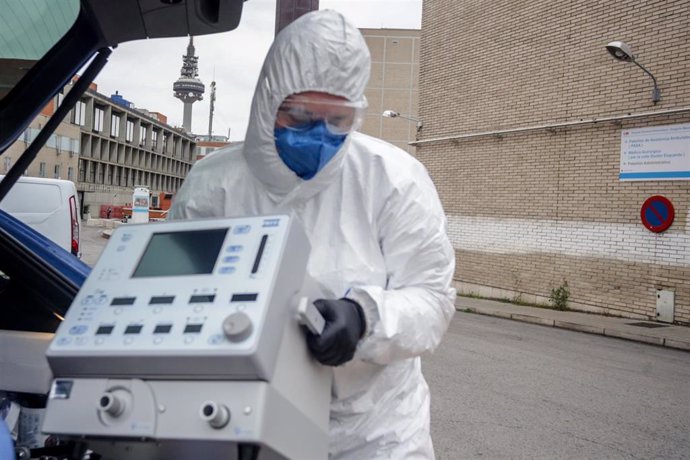 Un técnico protegido con un traje, guantes y mascarilla en el Hospital Gregorio Marañón, saca un respirador del maletero de su coche antes de montarlo en el Hospital, elemento imprescindible para muchos pacientes enfermos de coronavirus, en Madrid.