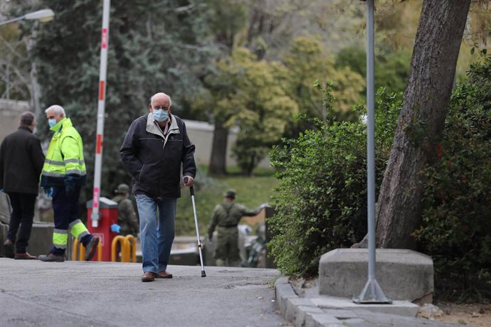 Un hombre con muleta y mascarilla pasa junto al área donde soldados del Mando de Ingenieros de Salamanca del Ejército de Tierra, una unidad de 34 militares, instalan un hospital provisional de entre 60 y 70 camas en las inmediaciones del Hospital Gregor