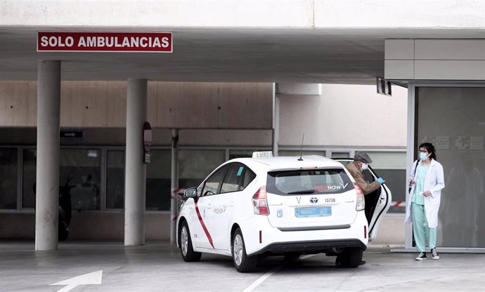 Un hombre se baja de un taxi y es recibidido por una sanitaria protegida con guantes y mascarilla en la entrada del Hospital de Fuenlabrada.