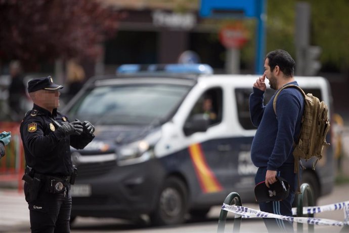 Un Policía Nacional habla con un transeúnte que caminaba por las inmediaciones del Palacio de Hielo de Madrid