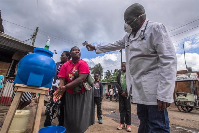 Un médico toma la temperatura mientras una mujer se lava las manos en Nairobi