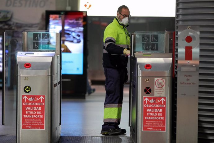 Un operario de limpieza desinfecta los torniquetes de la estación de cercanías Madrid Puerta de Atocha