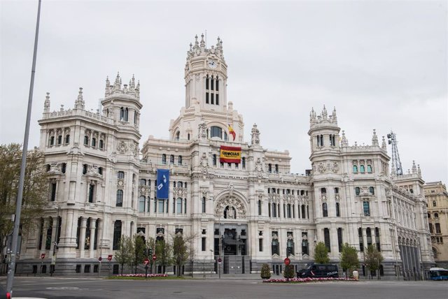 Banderas a media asta y bandera con el lazo que simboliza la lucha unida del pueblo de Madrid en la fachada del Ayuntamiento de Madrid durante el primer día del luto oficial por los fallecidos del COVID-19.