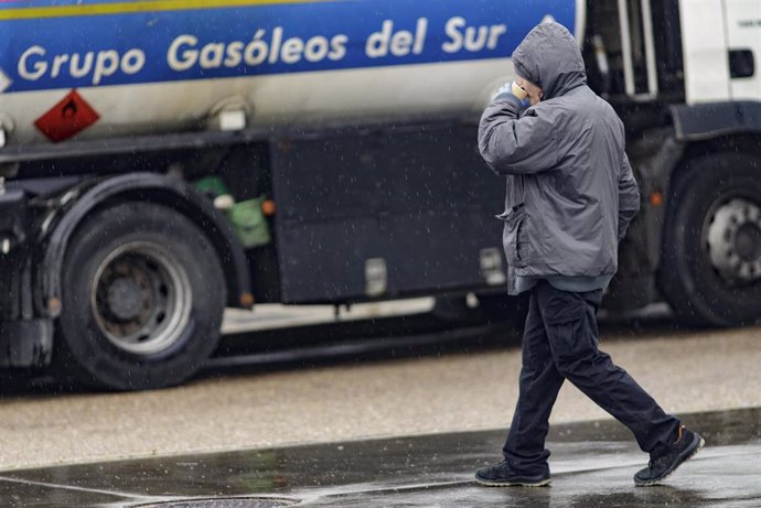 Un hombre pasa al lado de un camión de suministro de gasóleo en una estación de servicio en Madrid