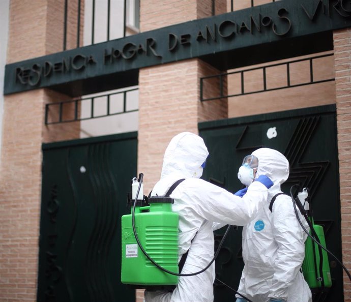 Dos militares de la UME totalmente protegidos se preparan antes de entrar en el Hogar de Ancianos Virgen de la Esperanza ubicado en San Sebastián de los Reyes para efectuar labores de desinfección y luchar contra la expansión del coronavirus