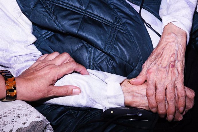 Una mujer cuidadora atiende a un anciano