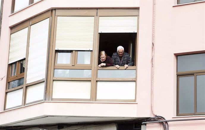 Unos ancianos confinados se asoman a su ventana durante la cuarentena por el coronavirus 