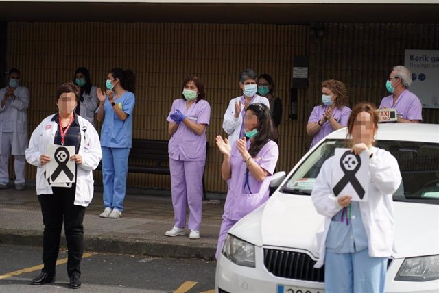 Trabajadores de Osakidetza (servicio vasco de salud)  del Hospital de Galdakao sostienen un lazo negro de luto mientras otros aplauden en recuerdo a la enfermera de 52 años fallecida por Covid-19 donde desarrollaba su labor profesional en la sexta planta.
