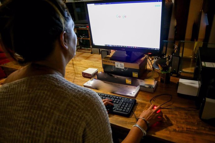 Una  mujer lee la pantalla de su ordenador, mientras trabaja en el despacho de su oficina