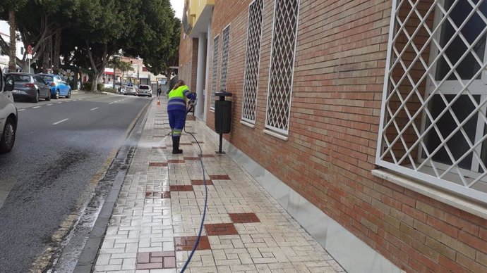 Una trabajadora de Limasa baldea y desinfecta una calle cercana a un centro de salud de la capital dentro de las labores contra el Covid-19